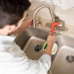 male plumber using wrench tighten water faucet kitchen seen up close